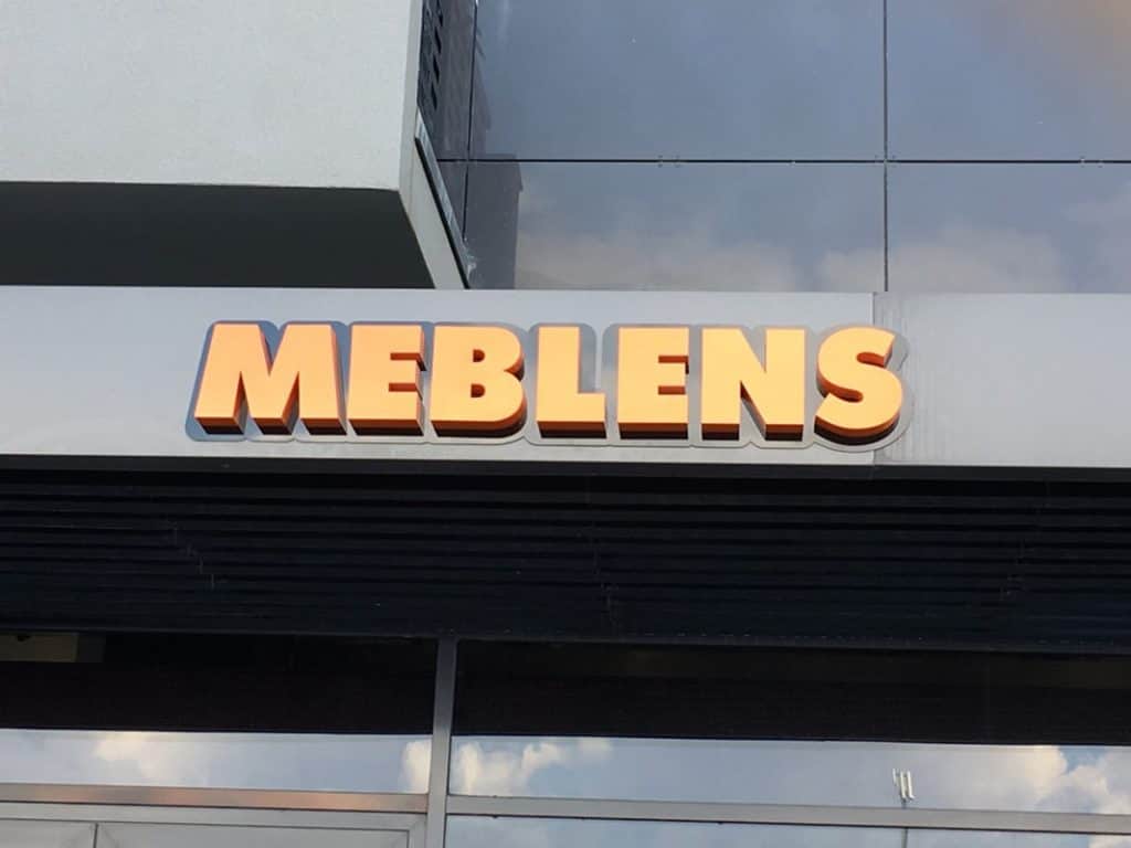 Об'ємні літери з назвою "MEBLENS" оранжевого кольору на фасаді будівлі