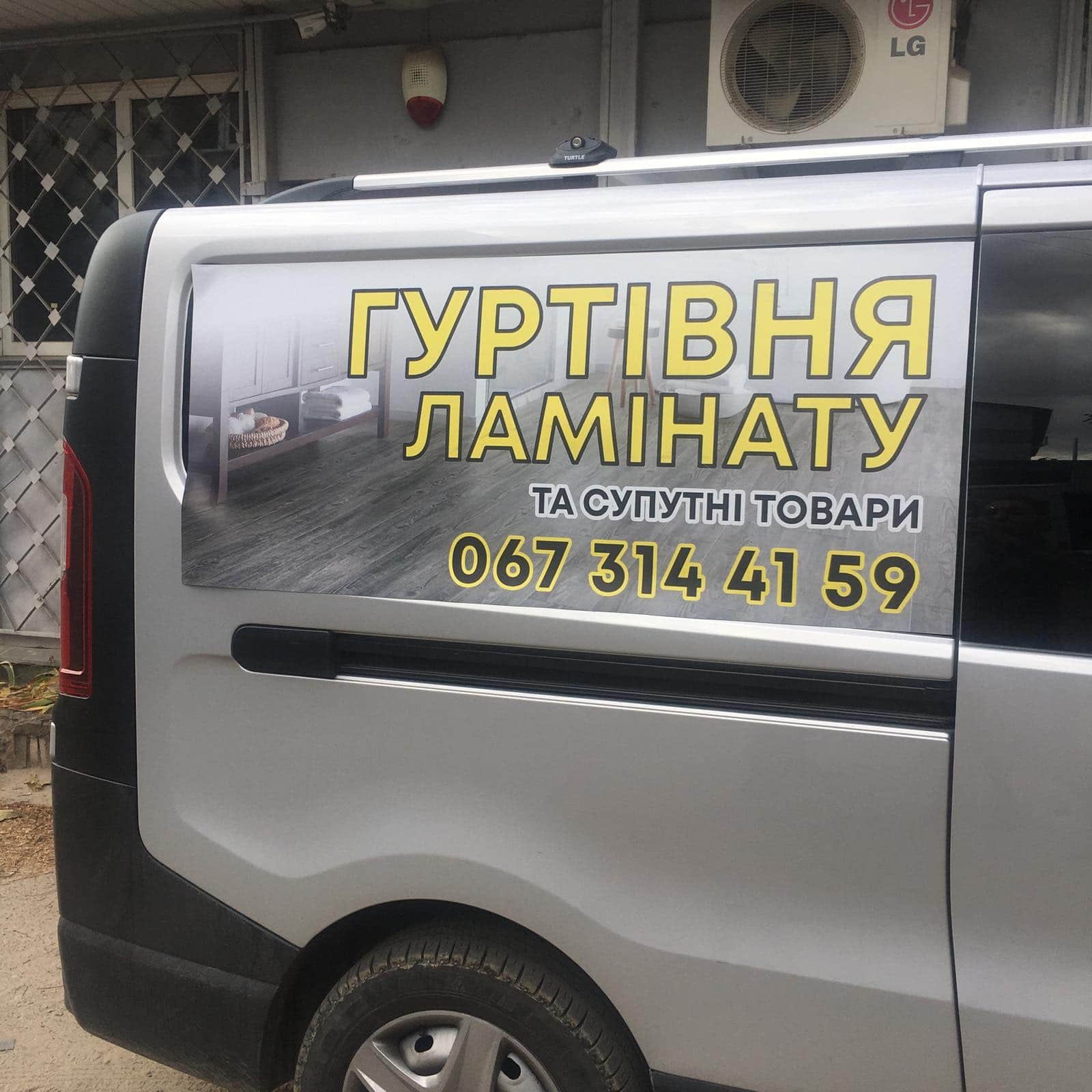 Рекламний напис на автомобілі з інформацією про гуртівню ламінату та супутні товари